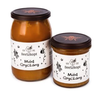 Dwa słoiki miodu gryczanego marki BeeSzkopt o różnych gramaturach na białym tle