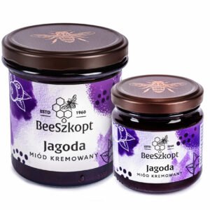 Dwa słoiki miodu kremowanego z Jagodą marki BeeSzkopt o różnych gramaturach na białym tle
