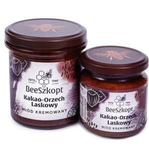 Dwa słoiki miodu kremowanego Kakao Orzech Laskowy marki BeeSzkopt o różnych gramaturach na białym tle