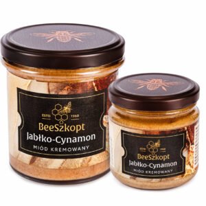 Dwa słoiki miodu kremowanego Jabłko Cynamon marki BeeSzkopt o różnych gramaturach na białym tle