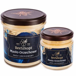 Dwa słoiki miodu kremowanego Masło Orzechowe marki BeeSzkopt o różnych gramaturach na białym tle