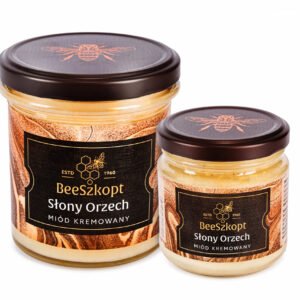 Dwa słoiki miodu kremowanego Słony Orzech marki BeeSzkopt o różnych gramaturach na białym tle